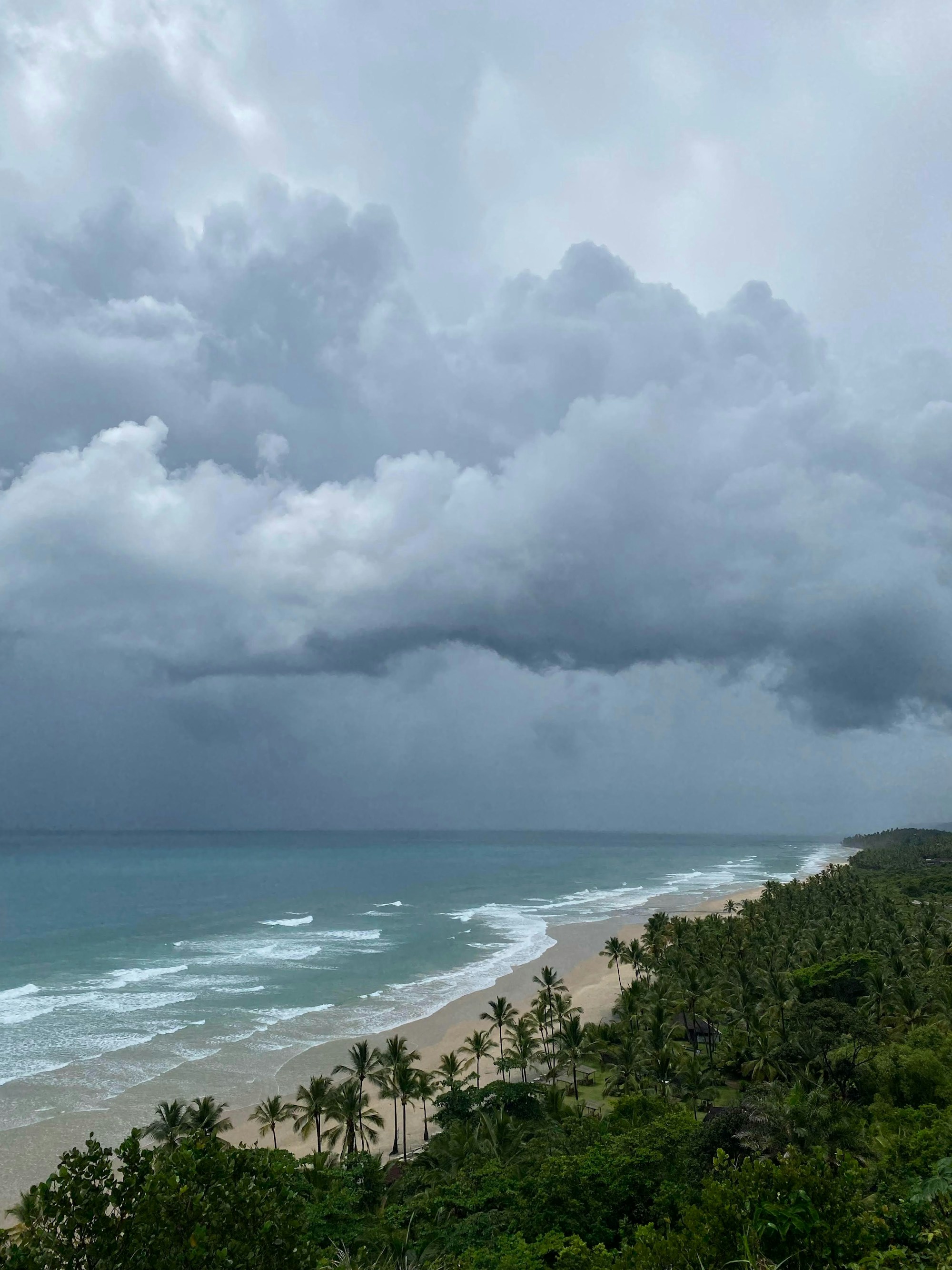 A wide beach in Itacaré under a broken, cloudy sky.